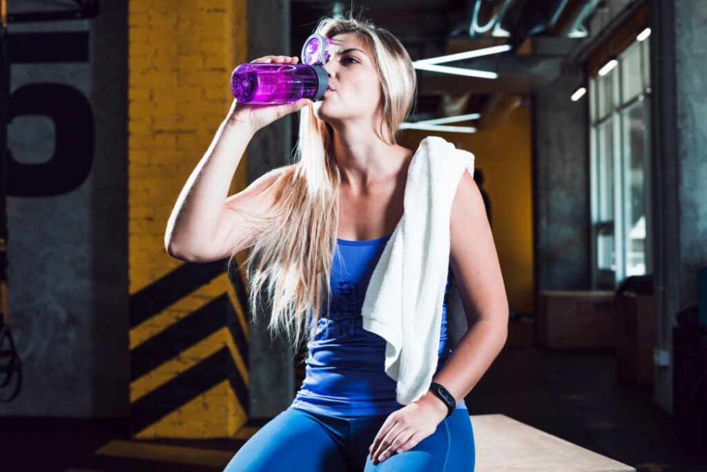 atleta mujer bebiendo agua gimnasio