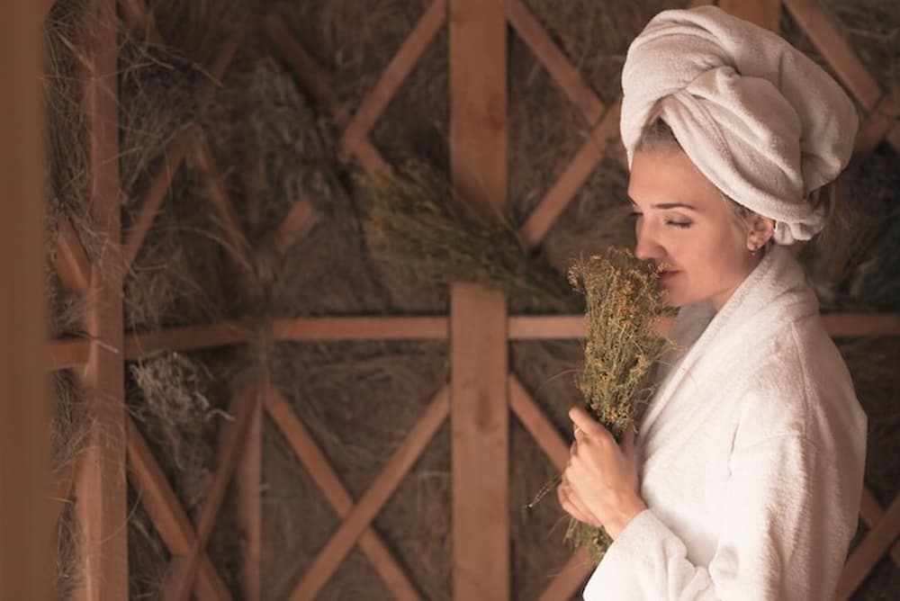 Mujer oliendo hiervas en una sauna